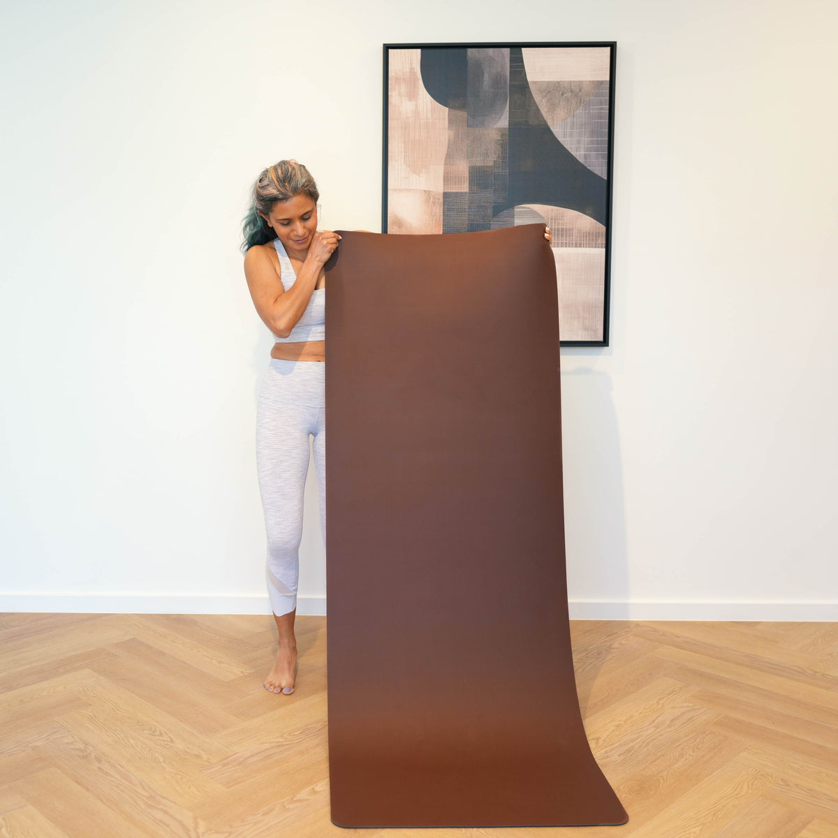 Woman unrolling a Mahogany extra-wide vegan leather yoga mat