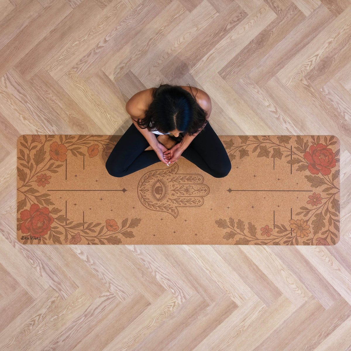 Person meditating on a Zenvibes Hamsa Harmony extra wide cork yoga mat with floral designs.