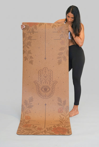 Woman holding a Zenvibes extra wide cork yoga mat with a Hamsa Harmony design.