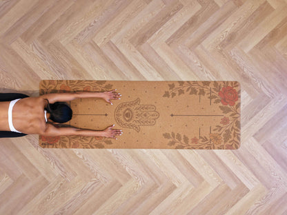 Top view of a person on a Zenvibes Hamsa Harmony extra wide cork yoga mat on a wooden floor.