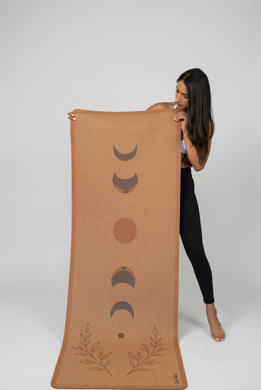 Woman holding a Zenvibes extra wide cork yoga mat with moon phase and botanical designs