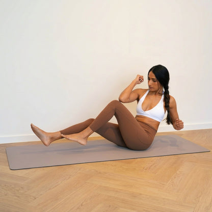 Woman doing a Pilates core exercise on a Sandstone vegan leather mat